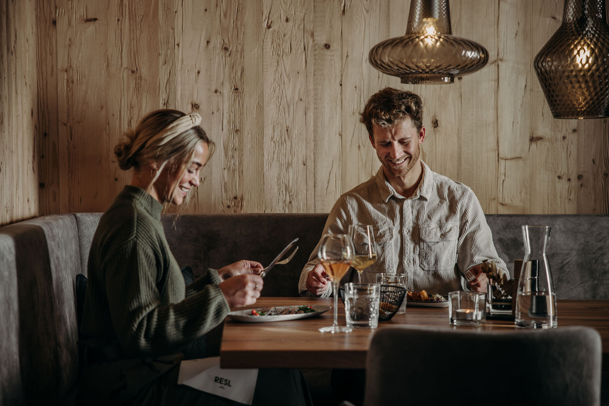 A couple enjoys a meal together in a cozy, warmly-lit restaurant